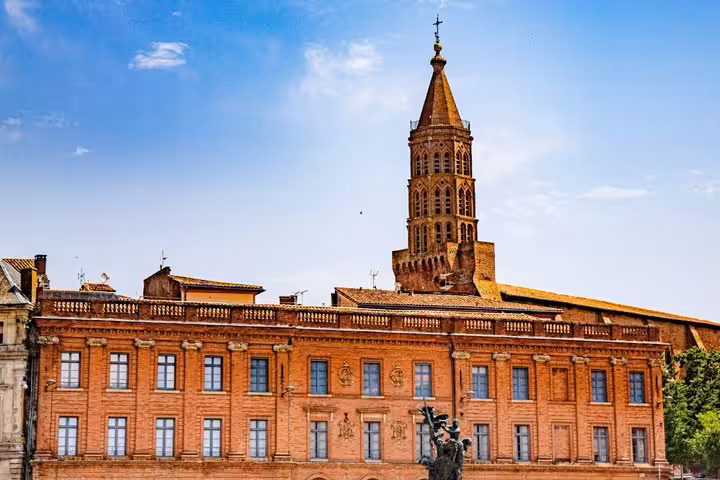 Red brick building and Gothic bell tower in Montauban, France under blue sky