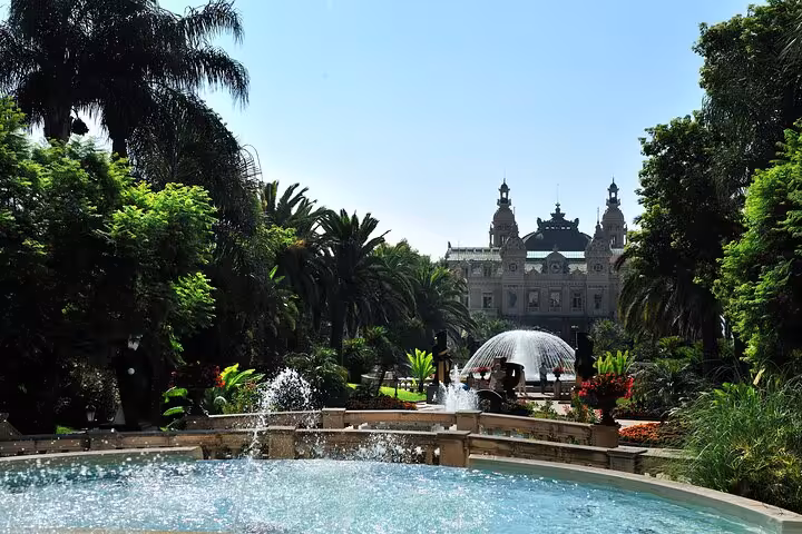 Fountain and gardens in front of Monte-Carlo Casino, Monaco, with palm trees and blue sky
