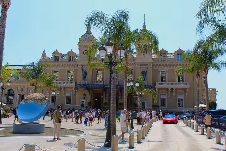Monte Carlo Casino facade with palm trees and tourists in Monaco's Place du Casino