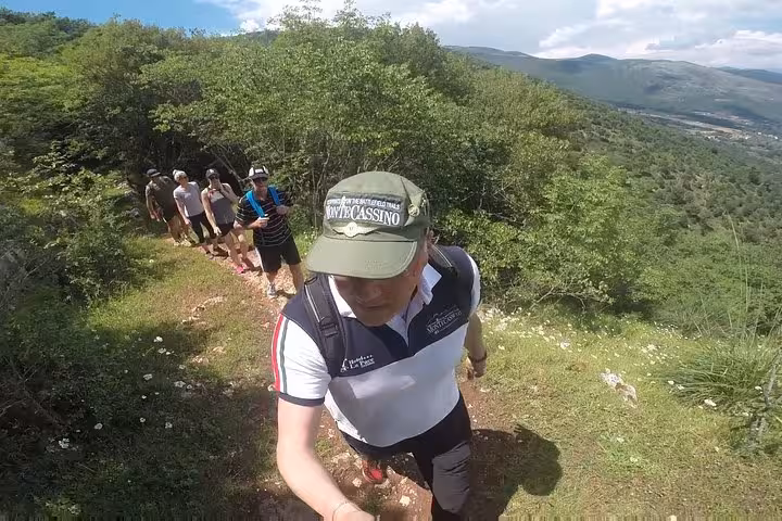 Group of hikers trekking along historic Monte Cassino mule tracks through lush green hills on a guided battlefield tour