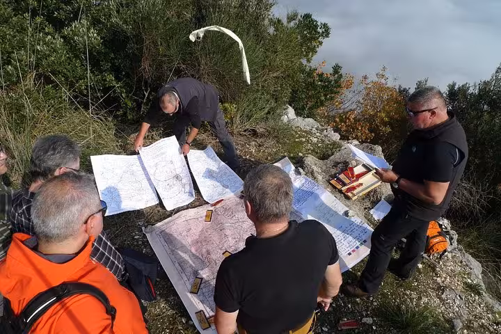 Tour guides reviewing detailed WWII battle maps on rocky Monte Cassino terrain during a historic battlefield hiking tour