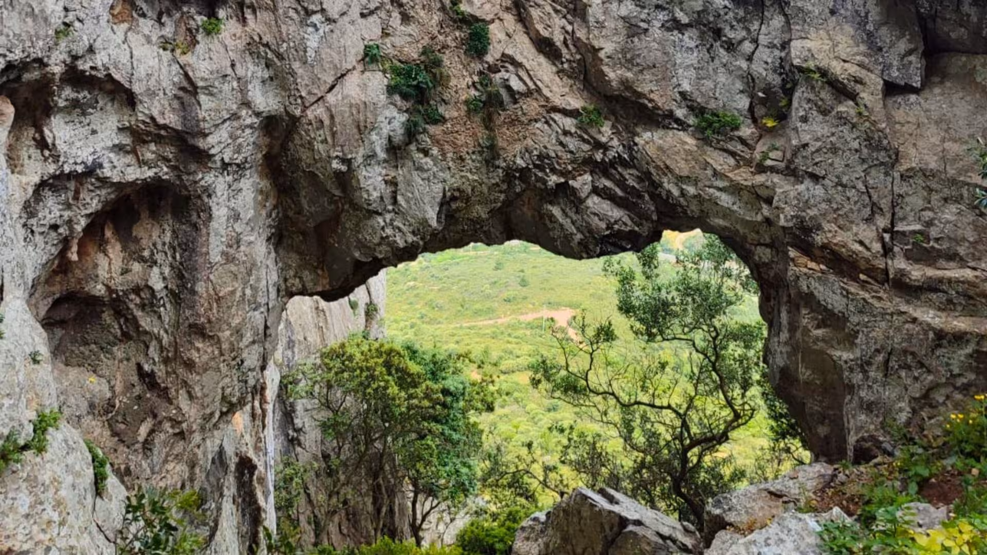 Natural rock archway offering a scenic view of lush greenery on the Monte San Giovanni canyoning trail.