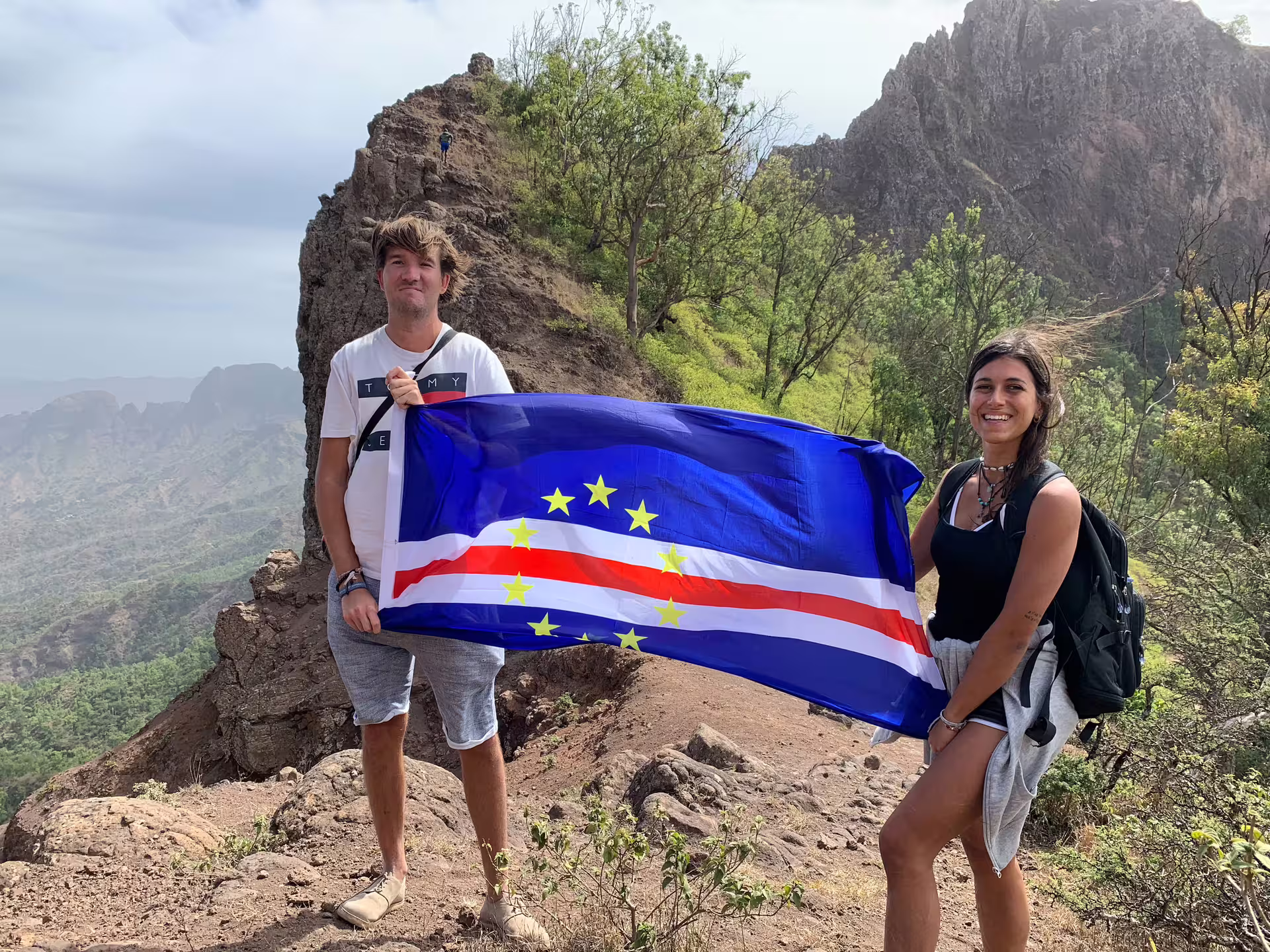 Hikers proudly display Cape Verde flag atop Monte Tchota, capturing scenic views at Pico D'Antónia summit hike.