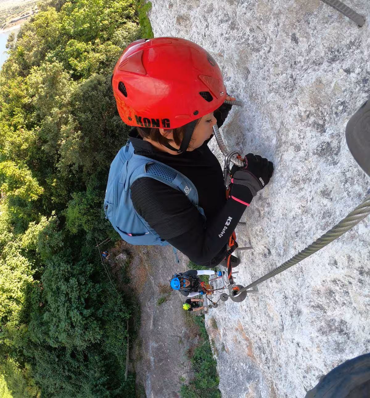 Adventurer climbing the via ferrata della Regina in Monteleone Rocca Doria with safety gear and stunning views.