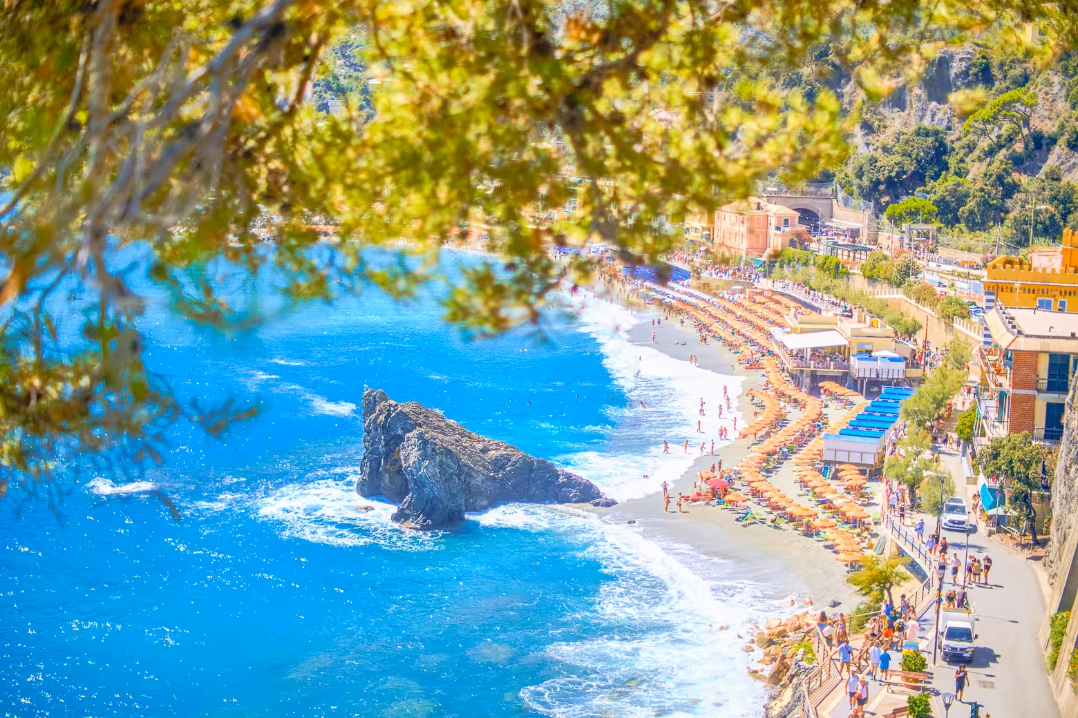 Aerial view of Monterosso beach with colorful umbrellas and clear blue water on Cinque Terre hiking tour.