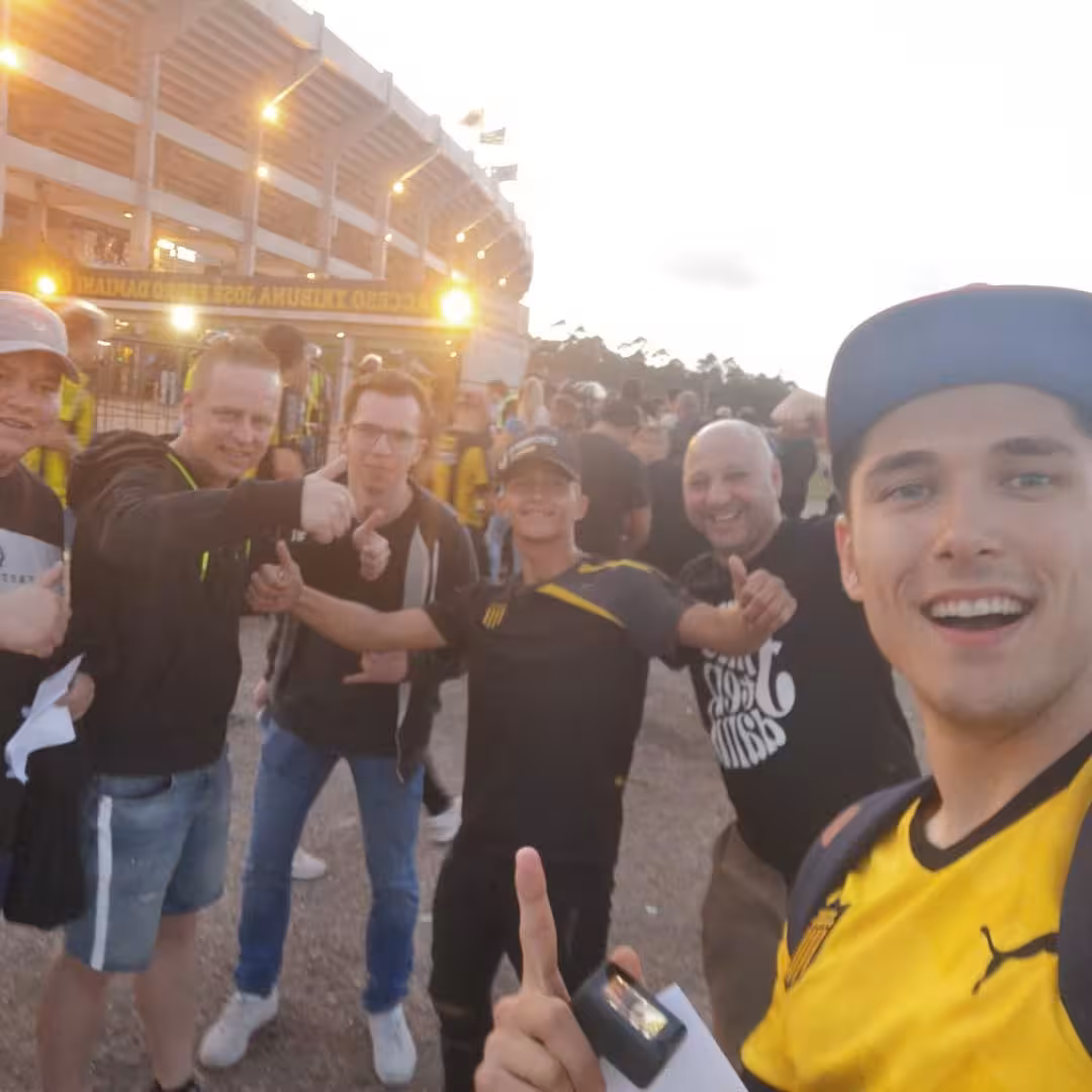 Travelers posing with Peñarol fans outside the Montevideo stadium before kickoff on a local soccer matchday tour