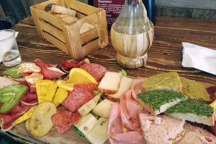 Traditional Italian charcuterie board with salami, cheese, and fresh fruit on a Monti District street food tour