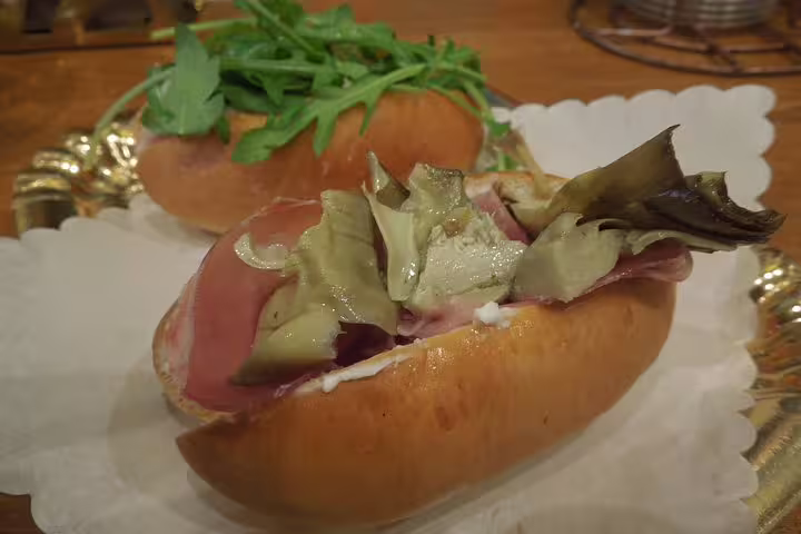 A delicious Roman street food sandwich filled with prosciutto and artichokes on a rustic bread roll served in Monti District.