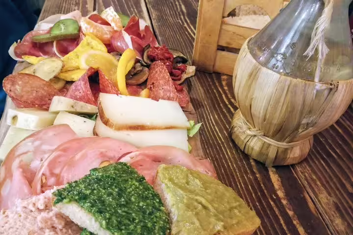 Traditional Italian charcuterie board with salami cheese cured meats and pesto bread on a rustic wooden table