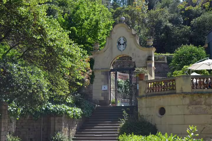 Ornate stone gateway with iron gates and heraldic emblem leading to Montjuic Castle, Barcelona