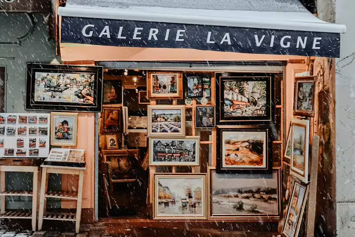 Galerie La Vigne art gallery storefront in Montmartre Paris displaying framed paintings in the snow
