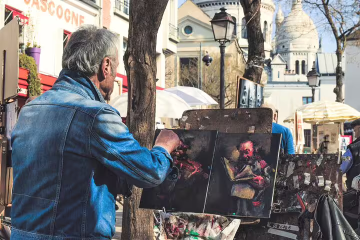 Artist painting in vibrant Montmartre with Sacré-Cœur in background, capturing Parisian culture on a full-day private tour.
