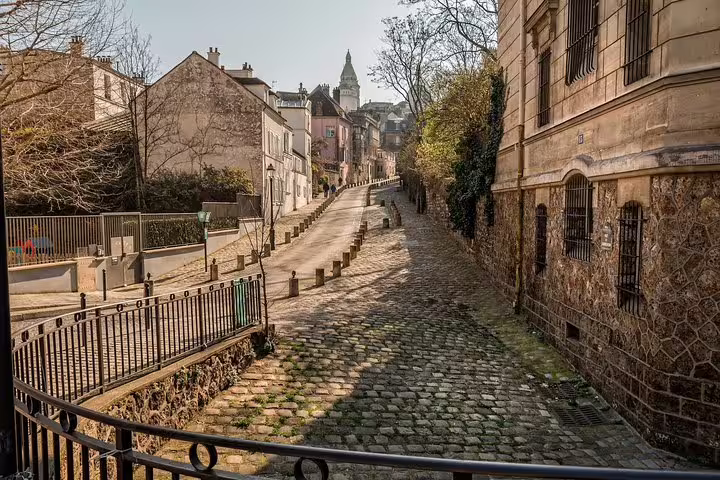 Cobblestone street in Montmartre with historic buildings and church tower, Paris