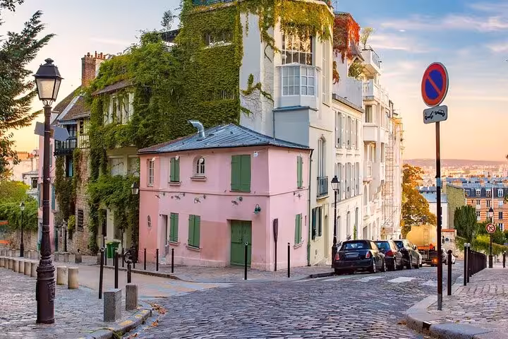 Charming cobblestone street in Montmartre Paris with pink building and ivy-covered walls at sunrise