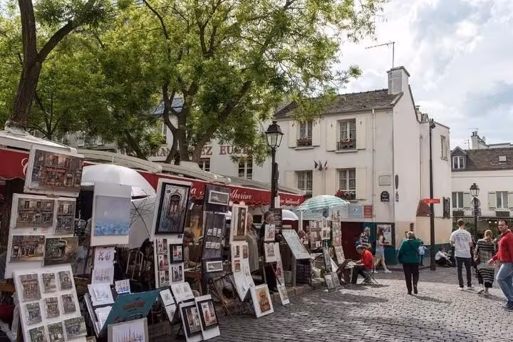 Hand holding a smartphone displaying a GPS walking tour app in Montmartre with Sacré-Cœur Basilica in the background.