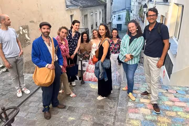 Group of tourists posing on colorful cobblestone street in Montmartre neighborhood, Paris