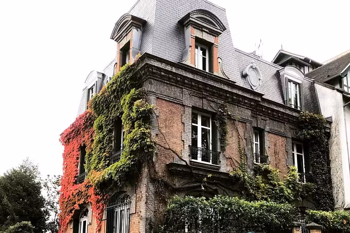 Ivy-covered historic brick building with mansard roof in Montmartre, Paris
