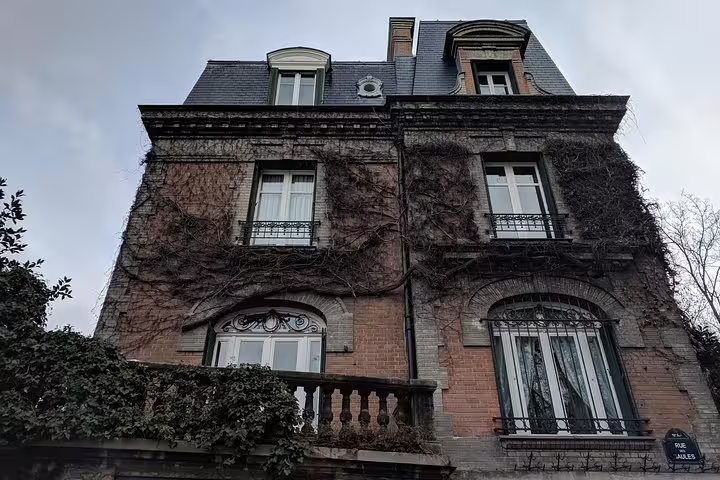 Ivy-covered historic brick mansion with ornate ironwork balconies and mansard roof in Montmartre, Paris