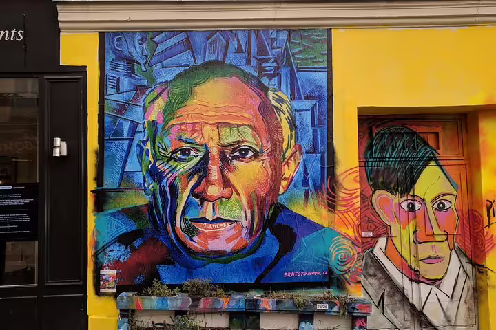 Colorful street art mural of Pablo Picasso on a yellow wall in Montmartre, Paris