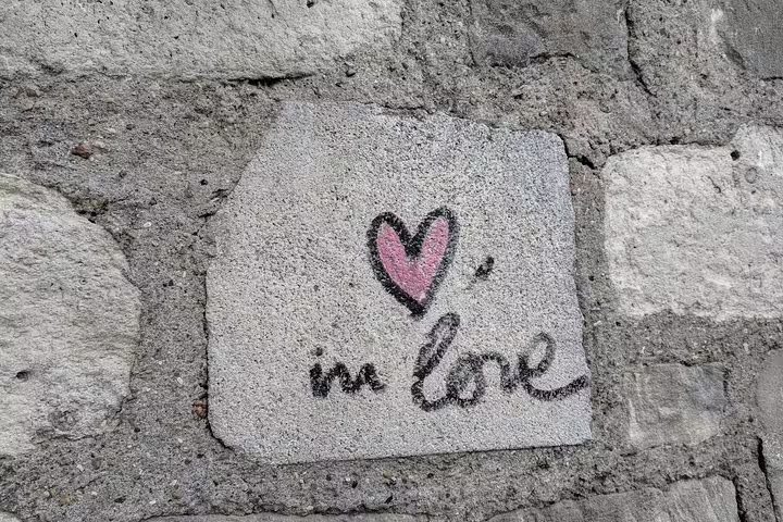Pink heart and 'in love' graffiti painted on a stone wall in Montmartre, Paris