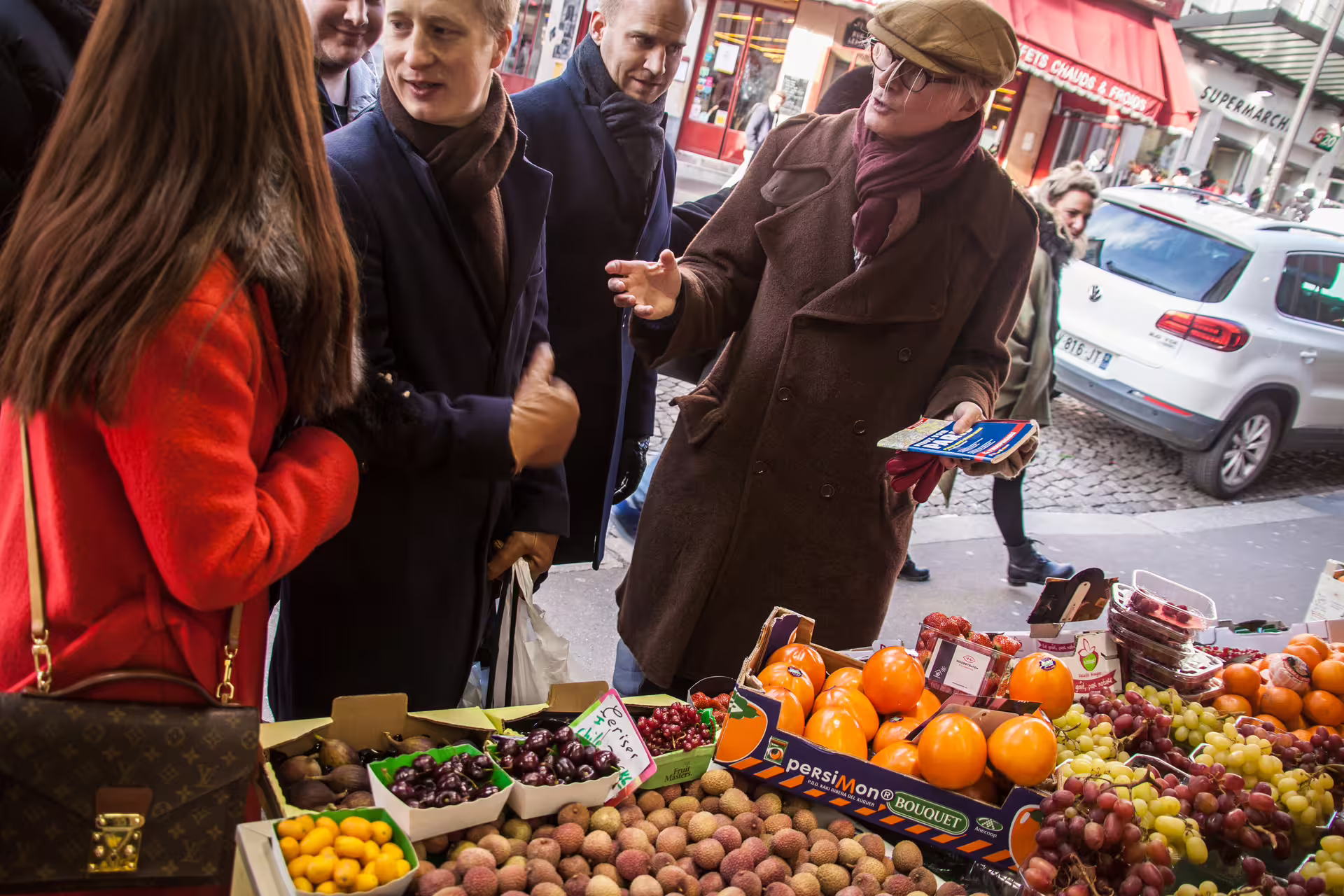 Group of tourists browsing fresh fruit stalls at an outdoor Paris market during a Montmartre walking tour