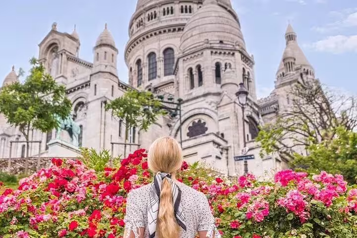 Woman with blonde hair gazing at Sacré-Cœur Basilica surrounded by blooming pink and red roses in Montmartre, Paris
