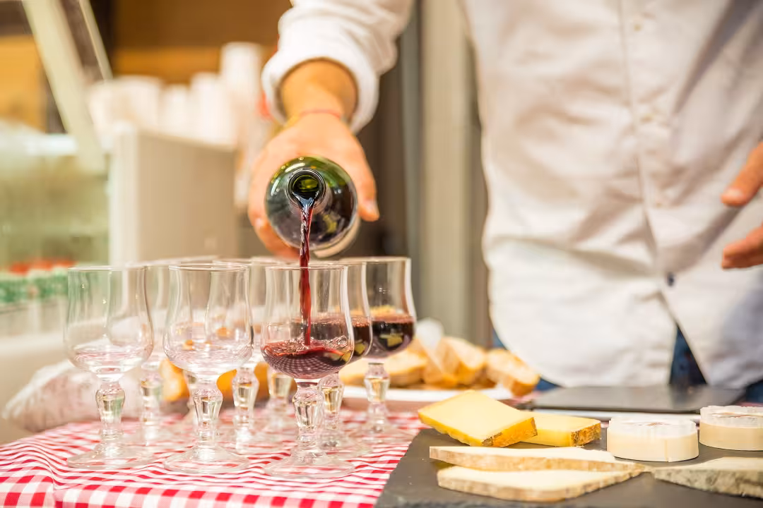 Red wine being poured into glasses, accompanied by a selection of cheeses during the Montmartre tasting tour.