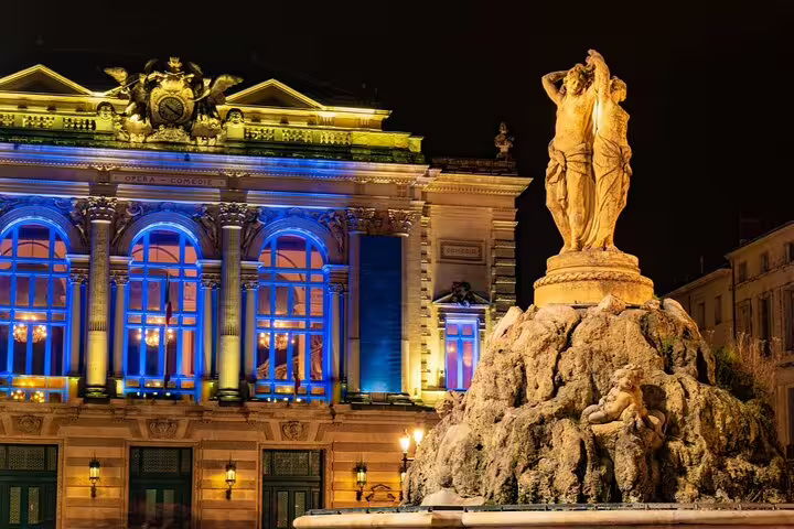 Illuminated Opéra Comédie and classical fountain statue at night in Montpellier, France