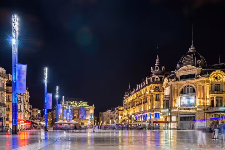 Place de la Comédie in Montpellier illuminated at night with ornate historic buildings and open plaza