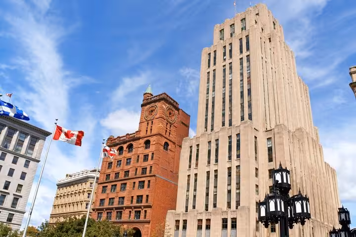 Historic red brick building and Art Deco skyscraper in downtown Montreal with Canadian flag
