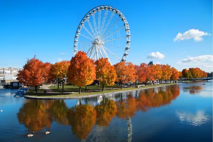 Ferris wheel and colorful autumn trees reflecting on calm water in Montreal Old Port