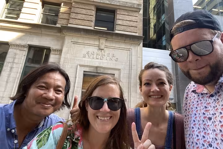 Four smiling tourists posing for selfie in front of the Sommer Building in Montreal