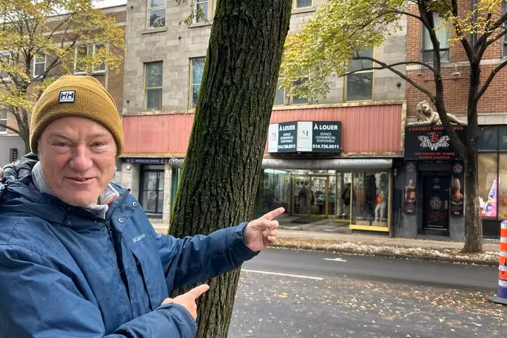 Tour guide pointing at historic Montreal street buildings during Prohibition Mystery walking tour