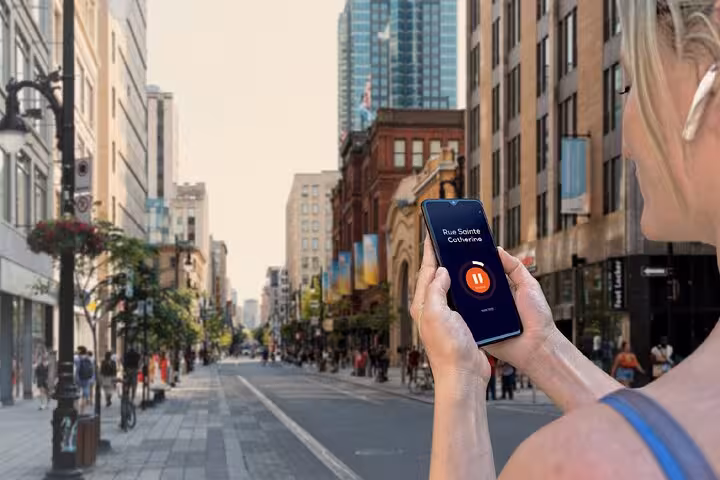Woman holding smartphone with audio guide app on Rue Sainte-Catherine street in Montreal
