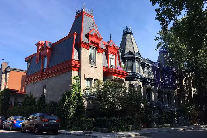 Colorful Victorian mansions with red and grey mansard roofs on a tree-lined Montreal street