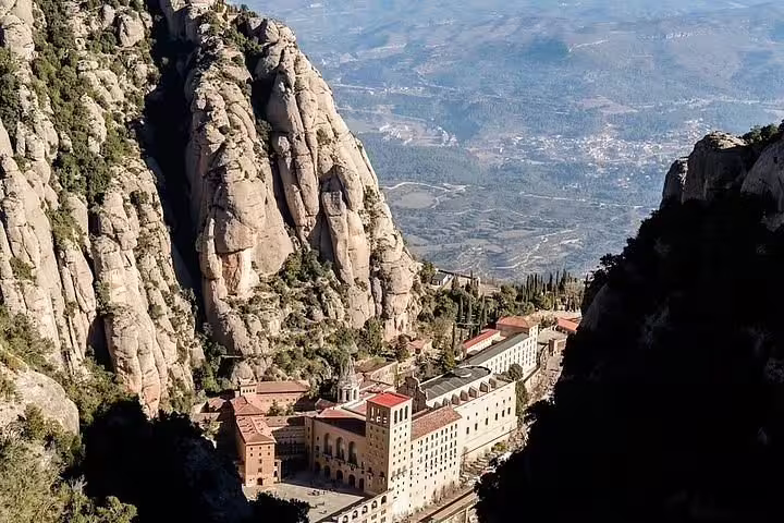 Aerial view of Montserrat Abbey nestled in dramatic cliffs, offering panoramic vistas of the Catalonian landscape.