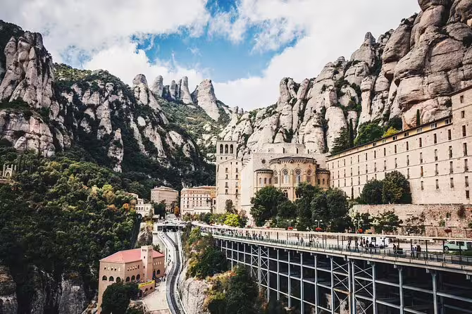 Tourists exploring the historic Montserrat Monastery against dramatic mountain cliffs.