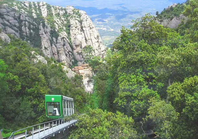 Scenic Montserrat mountain view with a green funicular train amidst lush greenery, ideal for private tour and wine tasting experiences.