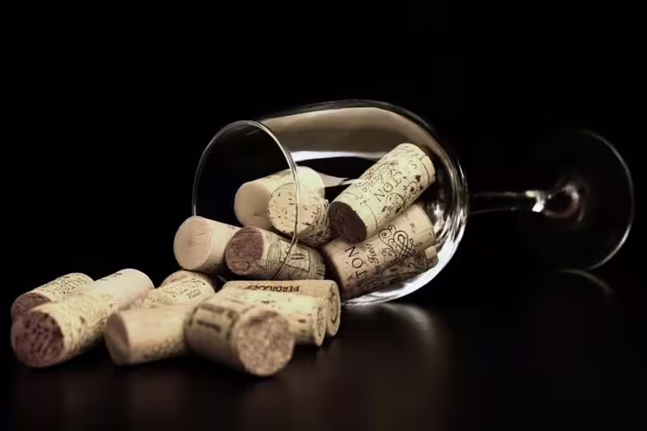 A collection of wine corks spills from a glass, symbolizing the authentic winery experience on the Montserrat tour.