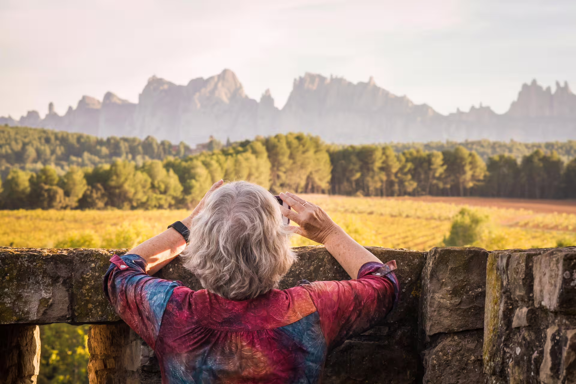 Traveler capturing stunning Montserrat mountain views amidst lush vineyards on a wine tour.
