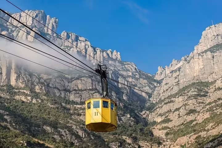 Yellow cable car ascending Montserrat, offering panoramic views of the stunning mountainous landscape.
