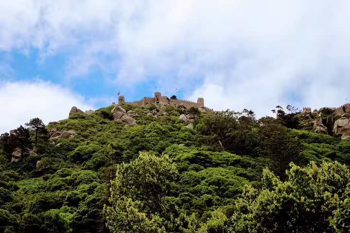 Majestic view of the Moorish Castle atop lush green hills in Sintra, Portugal, highlighting its historic allure and scenic beauty.