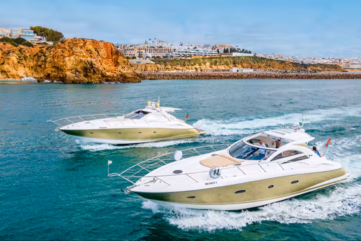 Two luxury yachts cruising Algarve coastline on Morning Cruise Plus, with sea cliffs and marina views in Portugal