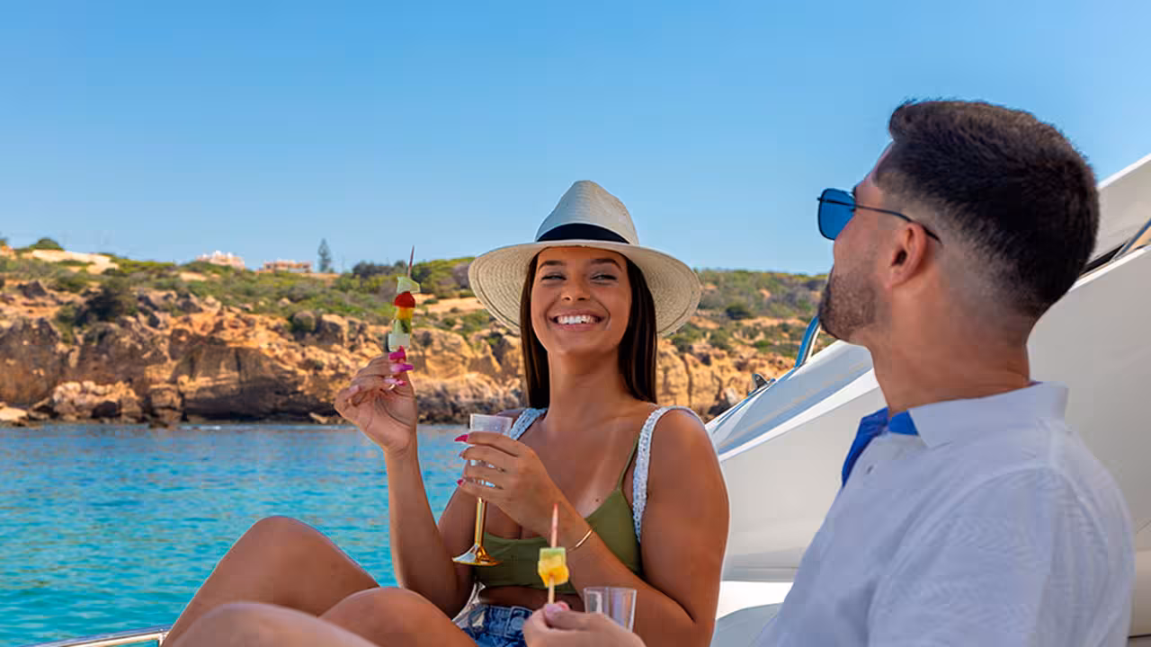 Couple enjoying fruit skewers and sparkling drinks on Morning Cruise Plus yacht along Algarve cliffs