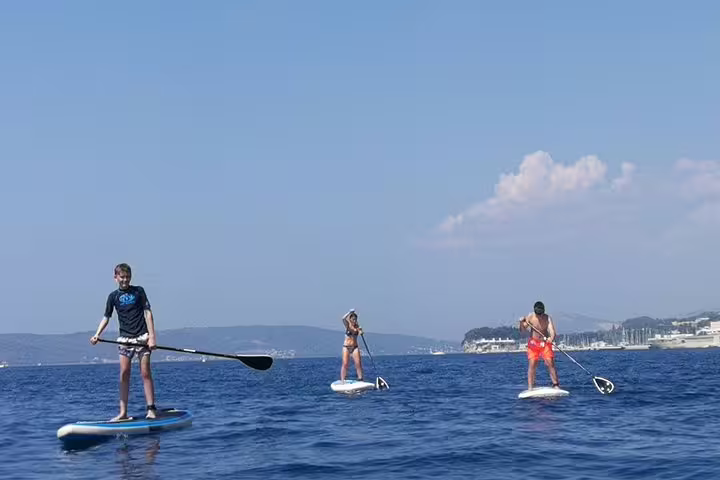 Group paddling on a morning stand up paddle tour in Split, Croatia, cruising the Adriatic with coastal views