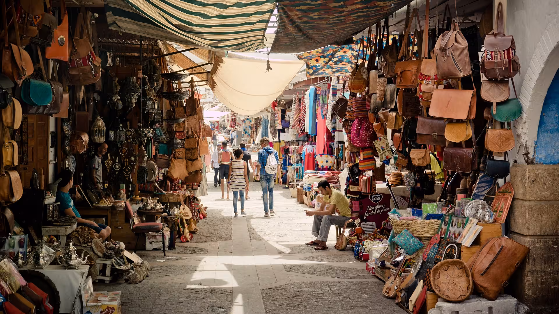 Bustling Moroccan souk market alley with leather bags and textiles, medina shopping on Timeless Morocco