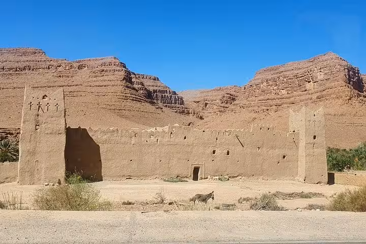 Ancient adobe structure set against rugged desert mountains on a Morocco group tour from Fes to Marrakech.