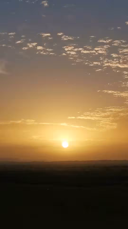 Golden sunrise over Morocco desert horizon with scattered clouds, scenic Sahara views on Best of Morocco tour