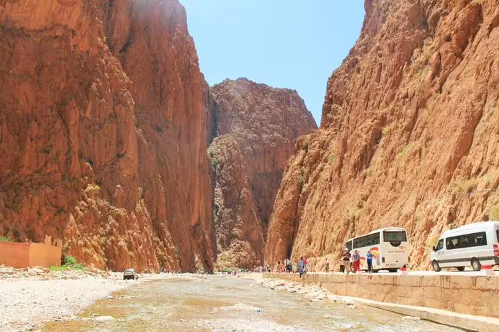 Tour bus driving through Todra Gorge canyon, popular Atlas Mountains stop on Morocco 10 days tour from Casablanca