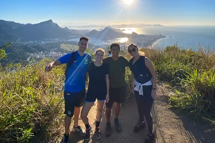 Group of friends poses at sunrise on Vidigal with panoramic views of Rio de Janeiro's beaches and mountains.